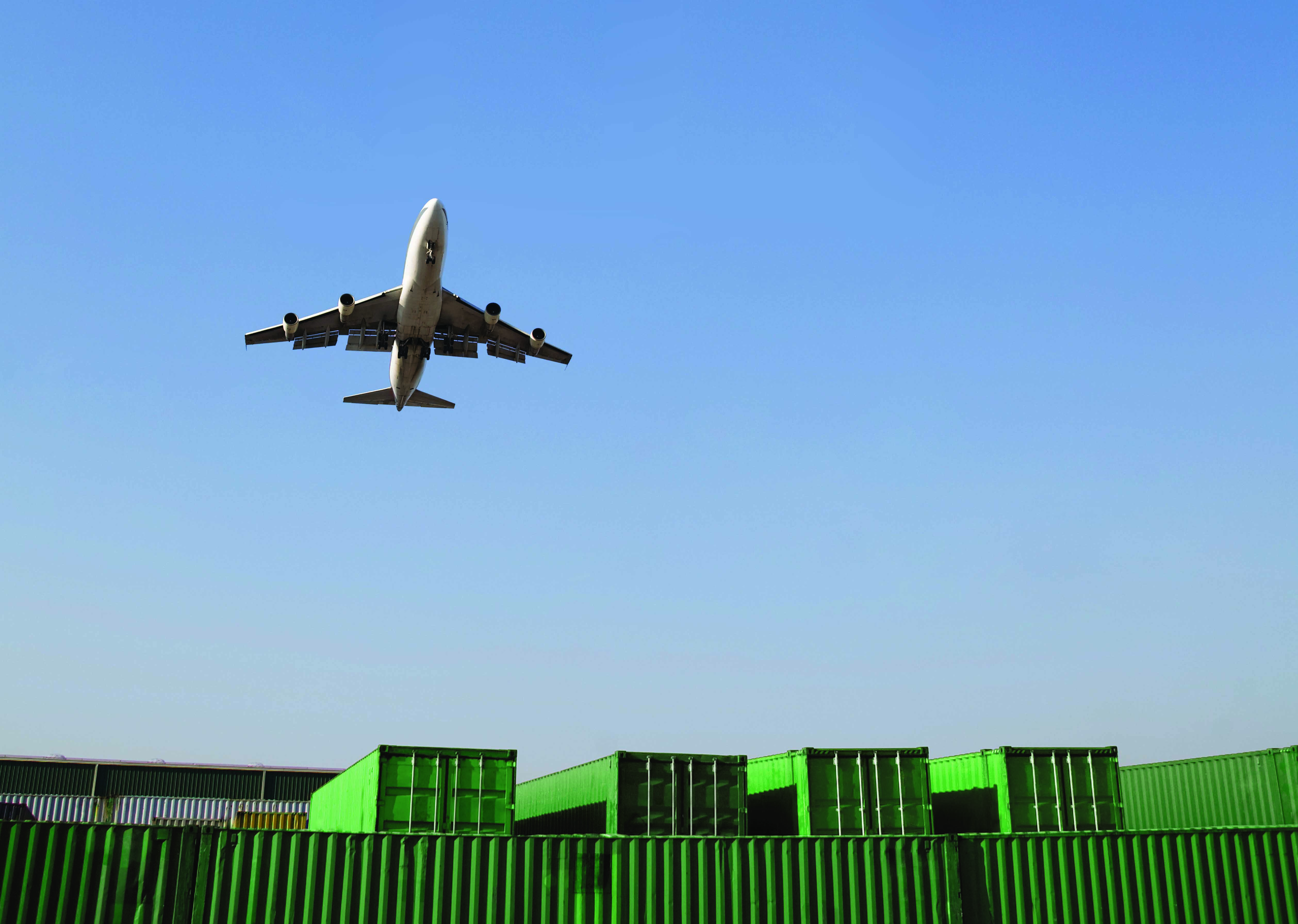 Airplane flying over shipping containers