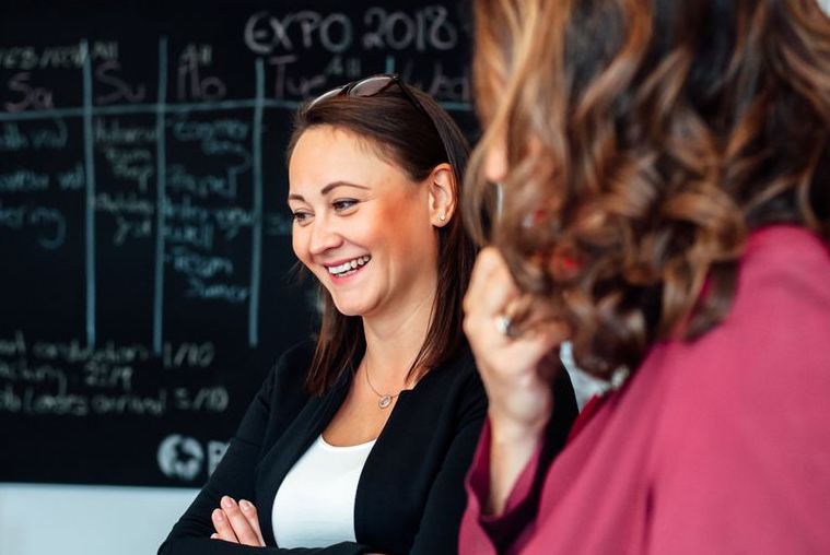 Two women standing in front of a chalkboard and smiling