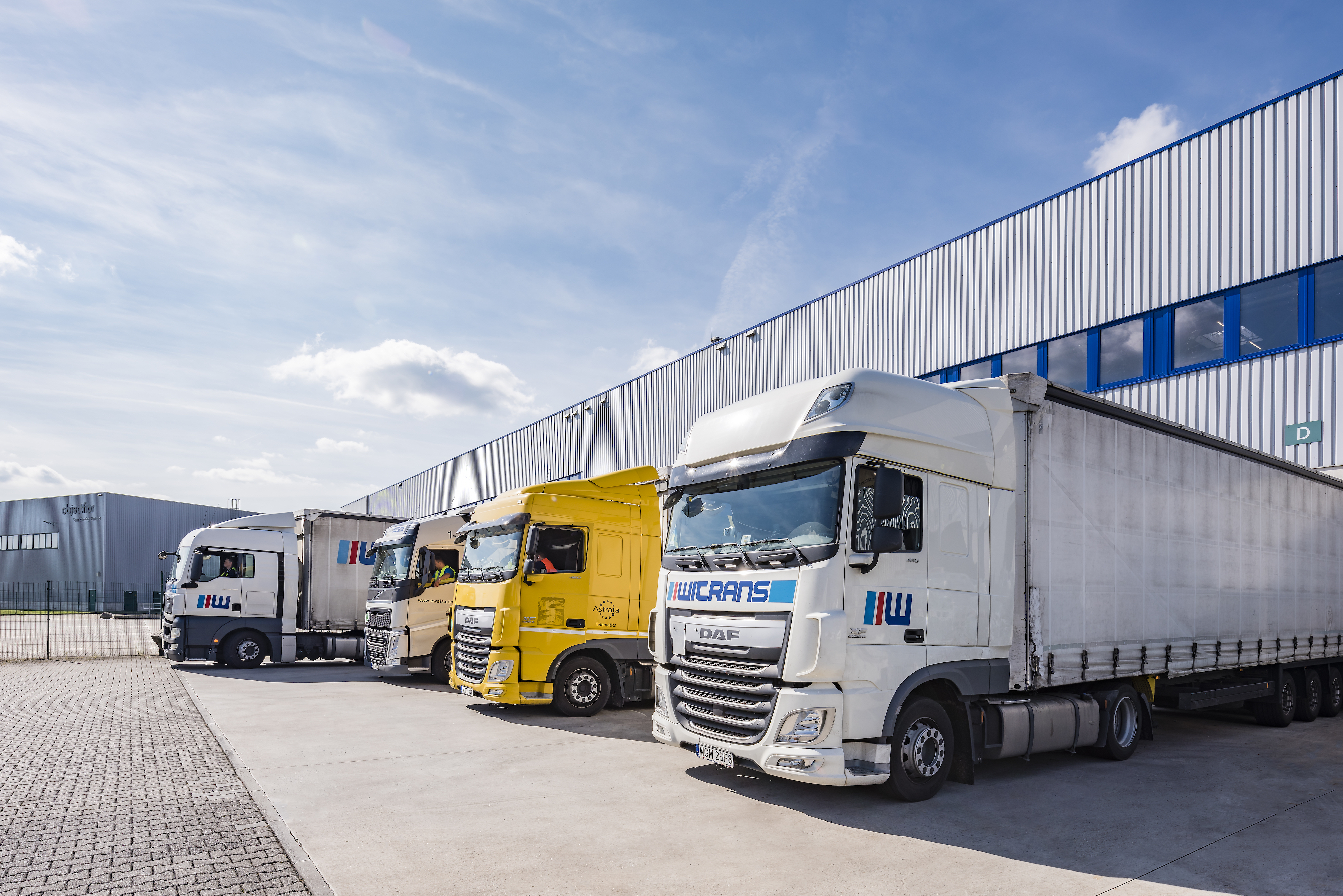 Angled view of warehouse exterior loading dock at Prologis Park Cologne in Cologne, Germany with four semi trucks up close