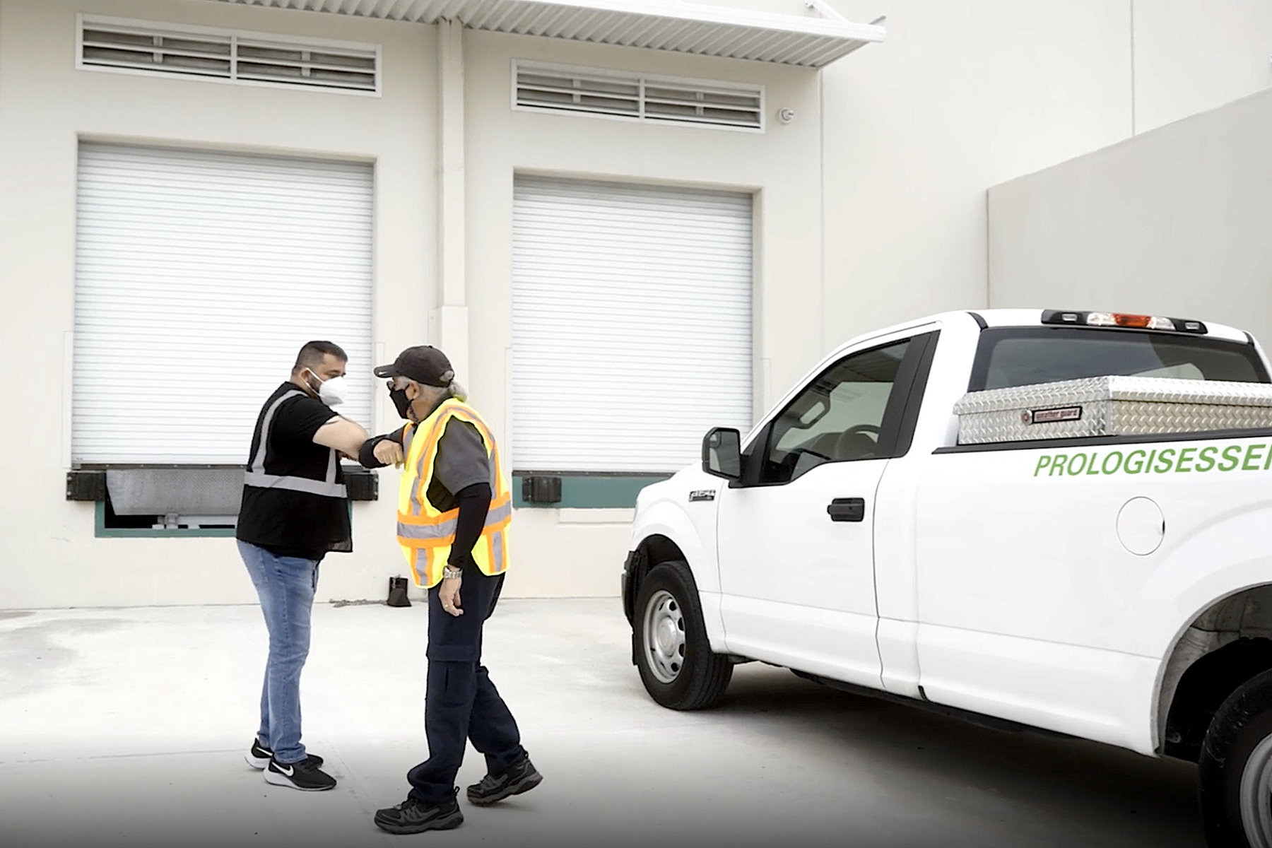 Workers greeting each other with an elbow bump.