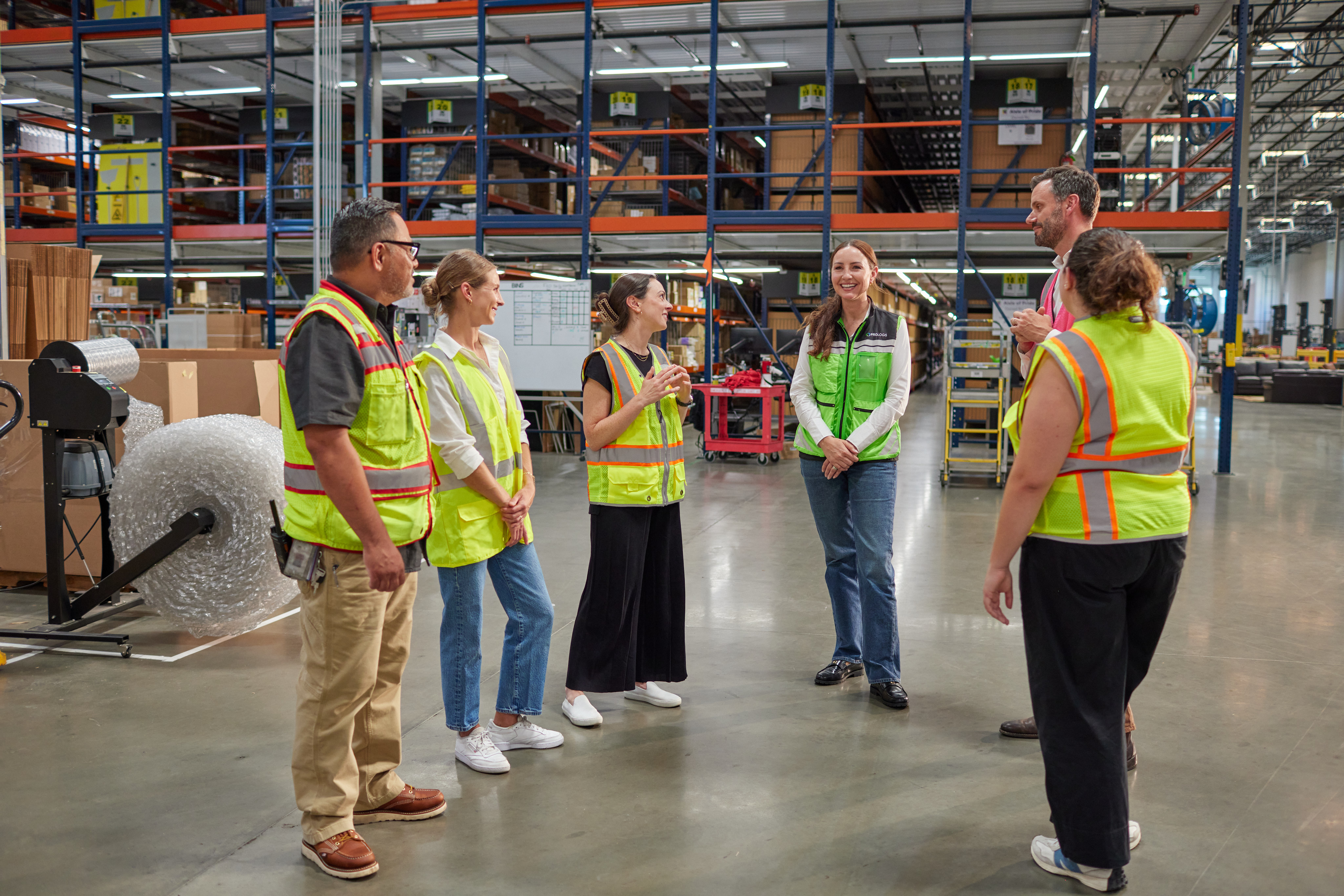 A group of people with safety vests in a warehouse