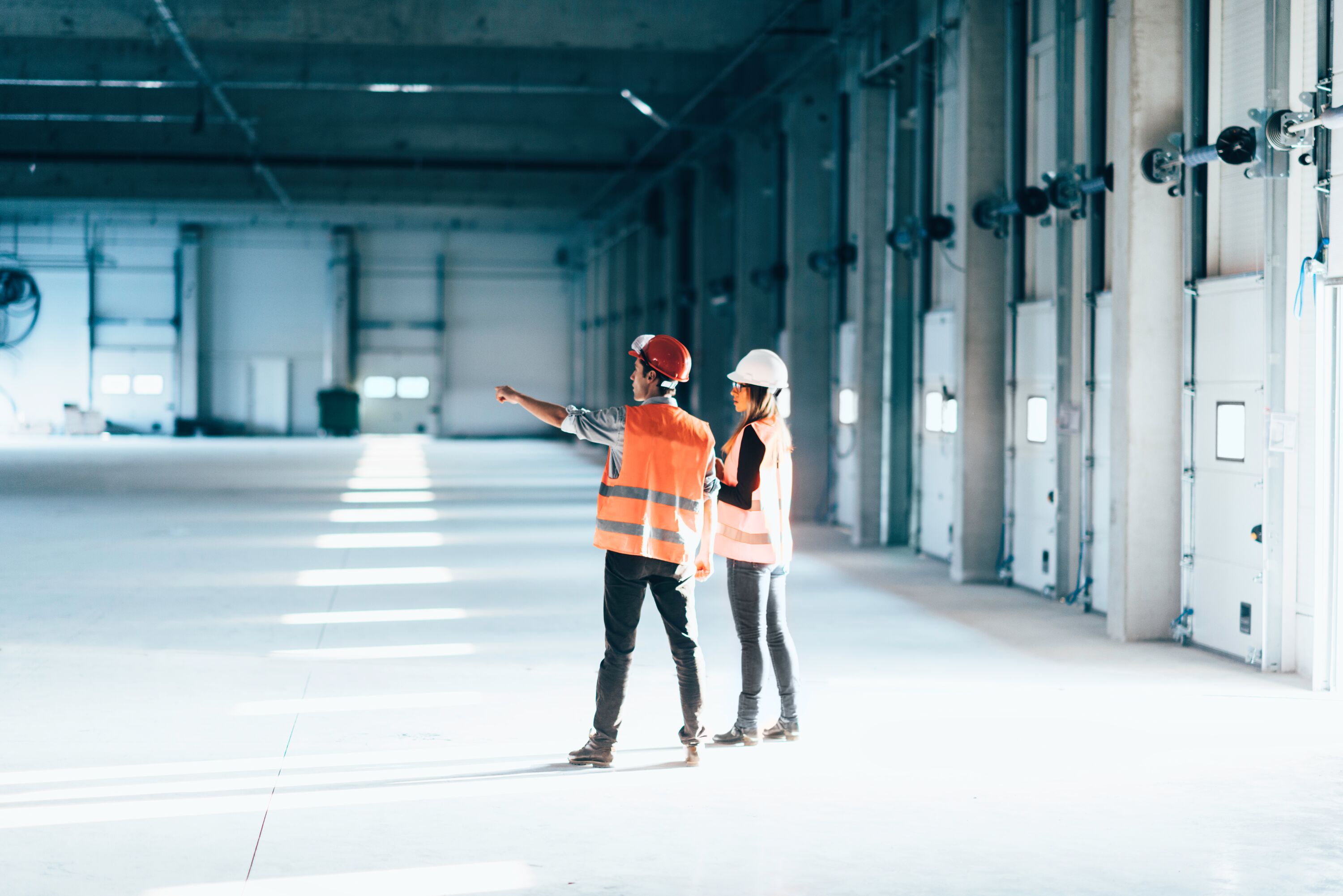 Two people in a large, vacant warehouse