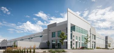 The front entrance of Prologis Business Center North with the dock doors and truck courts on the left side of the images, and landscaping and a parking lot to the right.