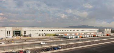 An exterior photo of Prologis Park Grande Building 1, with trucks in the truck court and an Amazon logo above the main entrance