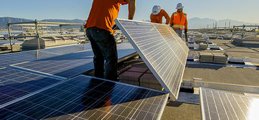 Three workers install solar panels at a location outside of Los Angeles