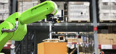 Robotic arm carrying a box in warehouse
