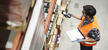 A worker uses a handheld scanner to check inventory inside a distribution center