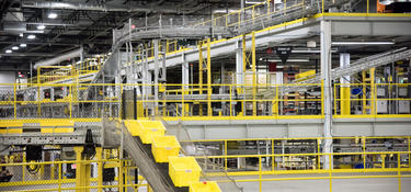 A photo of a warehouse conveyor racking system, with yellow boxes moving along the conveyor.