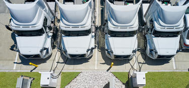 An overhead view of four electric fleet trucks charging at an EV charging station