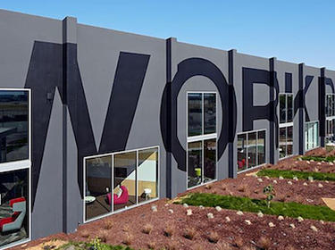 The side of a building with the word "workplace" painted across.