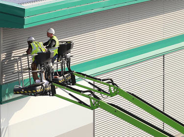 Photo of two workers on a cherry picker looking at the exterior of a warehouse at Prologis West London DC2