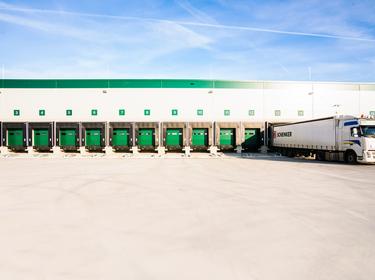 A photo of green dock doors at Prologis Budapest Sziget with a DB schenker truck parked outzide and blue sky above.