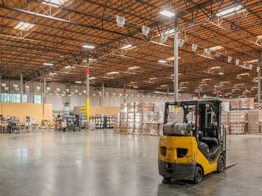 A shot of a yellow forklift inside Proloigs Kaiser DC2, with product stacked on the floor of the warehouse