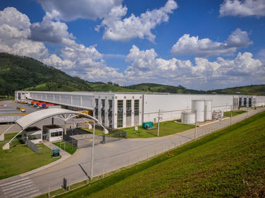 An exterior shot of Prologis Cajamar Building 1, with trucks parked in the truck court and a lush green hill in the background