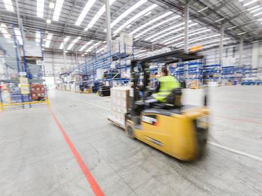 A shot of a yellow forklift in motion inside of a warehouse