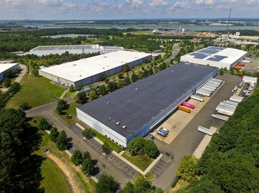 An exterior aerial shot of Prologis Edison with trucks parked in the truck court, and a lush green landscape surrounding
