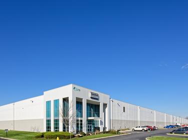 A photo of the main entrance of Prologis Carlisle 7. the building is grey and white with a MasterBrand logo above the front door. Cars are parked in the lot to the right
