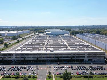 An Aerial photo of Prologis Ports Carteret 3 showing the roof and a busy parking lot, surrounded by other buildings, roads and green trees