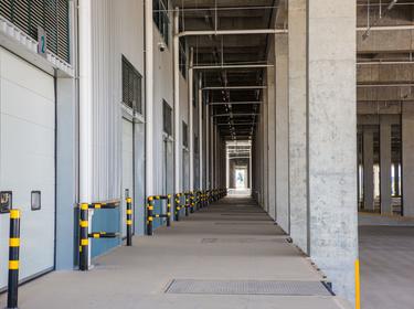 A photo of dockdoors at Prologis Chengdu Longquan Logistics Center. The camera is facing down a long hallway with dockdoors on the left, and a covered truck court on the right.
