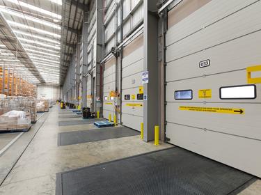A photo of the interior dock doors at Prolgois RFI DIRFT Sainsbury. The dock doors have yellow safety signage on them, and in the background there is tall orange racking.
