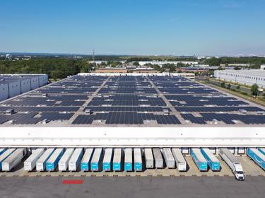 An aerial photo of Prologis ports carteret showing solar panels on the roof, and white and blue trucks in the truck bays