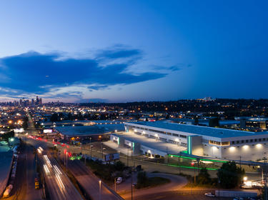 Prologis Seattle Georgetown Crossroads in Seattle, Washington at night with green glowing neon lights and Seattle skyline in the distance