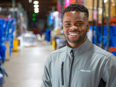 Prologis maintance tech, Max Igwe, wearing Prologis branded jacket posing in warehouse in California.