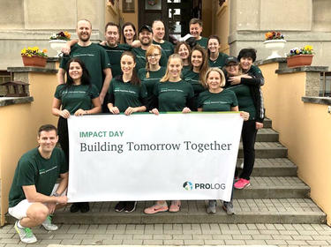 A large group of Prologis employees pose together with the sign Building Tomorrow Together for IMPACT Day 2019 