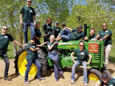 A group of Prologis employees posing with John Deere tractor for IMPACT Day 2018 