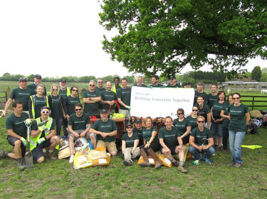 A group of Prologis employees posing together on a farm with Building Tomorrow Together sign for IMPACT Day 2018 