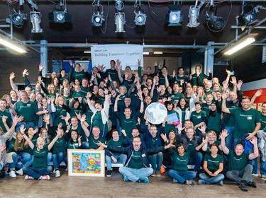 A large group of Prologis employees pose together with the sign Building Tomorrow Together for IMPACT Day 2018 