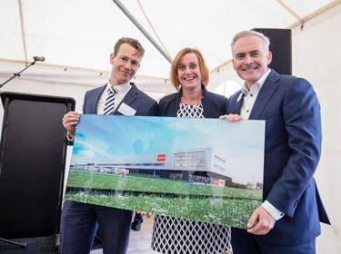Three team members hold a finished picture at a groundbreaking ceremony in Nieuwegein