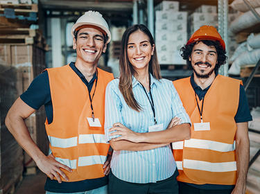 Three members of a warehouse team smiling confidently at the camera