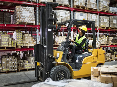 A warehouse worker drives a forklift inside a distribution center