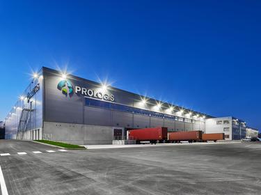 Angled night shot of semi trucks in loading docks at Prologis Datteln Distribution Center 1 in Datteln, Germany, light flares on building and large Prologis logo