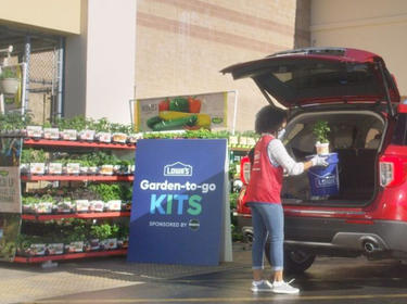 A Lowe's Employee loading packages into a customer's car.