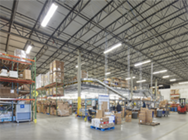 An interior photo of a warehouse whowing LED lighting and forkifts moving around
