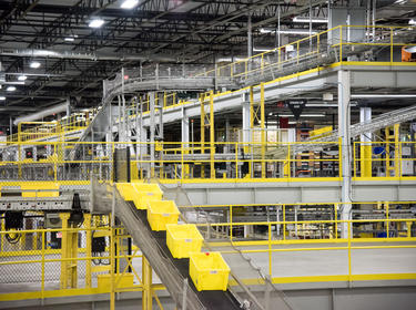 A photo of a warehouse conveyor racking system, with yellow boxes moving along the conveyor.