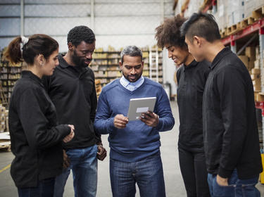 A diverse team looks at a tablet inside a distribution center