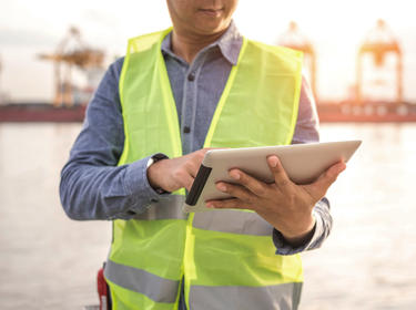 Worker wearing a yellow vest holding an iPad