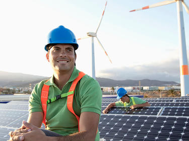 A man in a hardhat sitting near a bank of solar panels