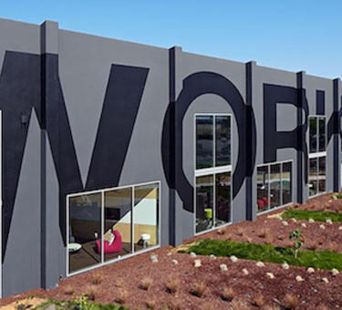 The side of a building with the word "workplace" painted across.