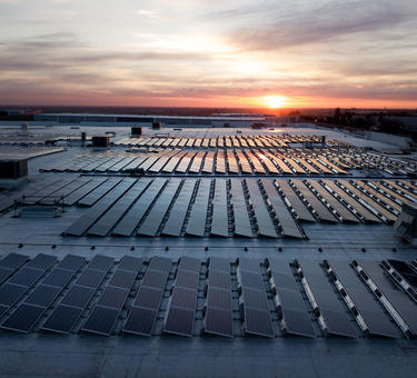 A warehouse rooftop covered in solar panels at sunset