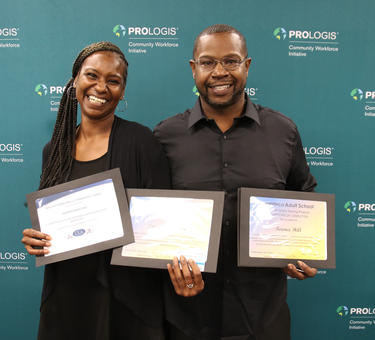 A man and woman holding certificates they earned in the CWI program