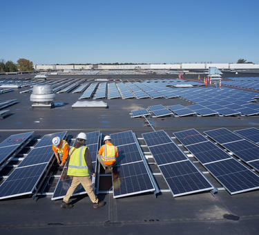 Three men working on solar panels on the roof of a Prologis building