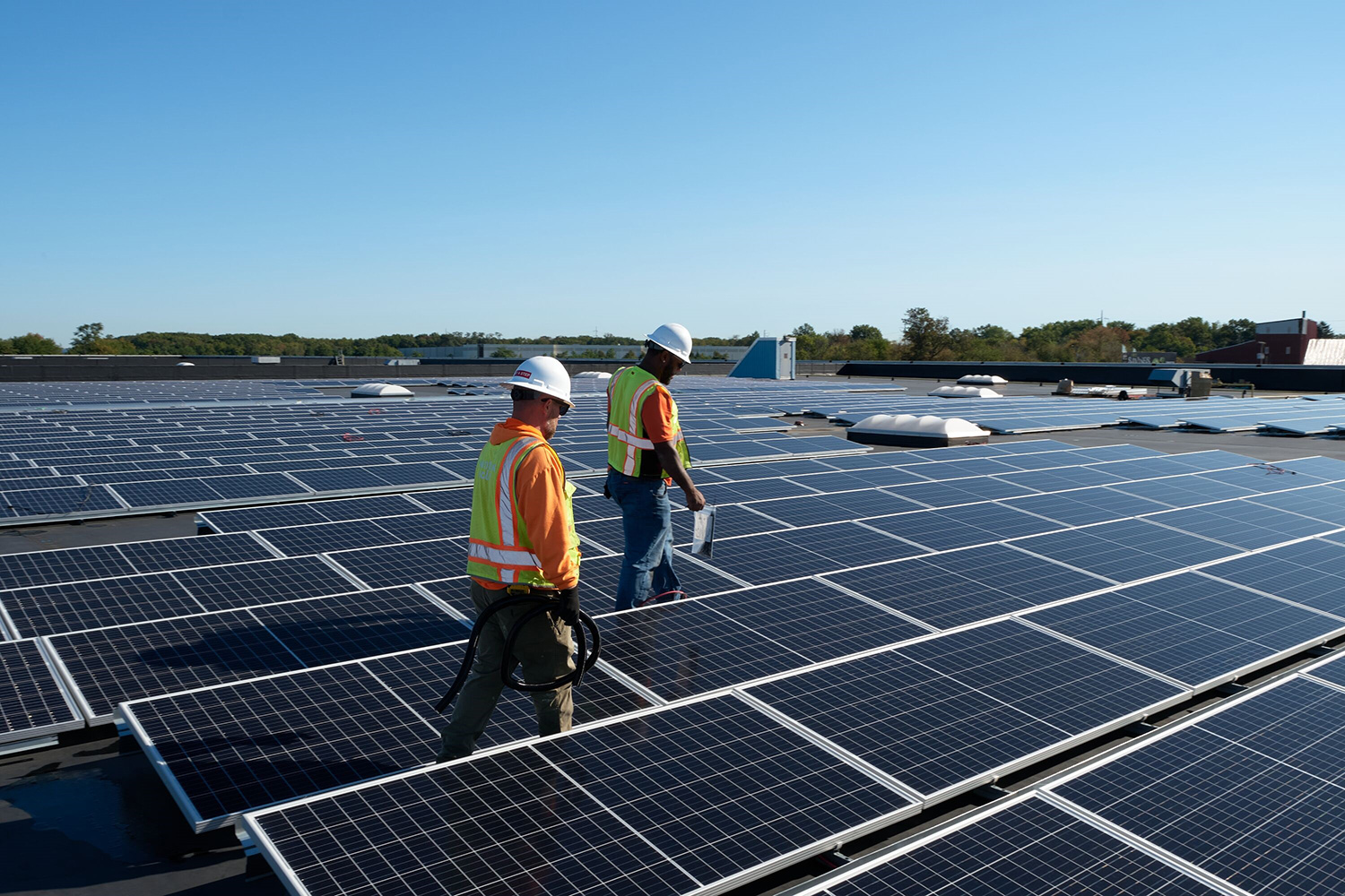 Workers on roof of warehouse with Solar panels