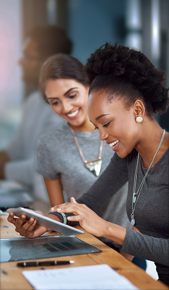 Two women smiling and looking at an iPad Two women smiling and looking at an iPad