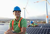 A man in a hardhat sitting near a bank of solar panels