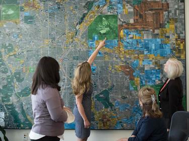 4 women looking at a map of the Denver area on a wall