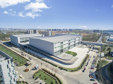 Aerial view of multi-story Prologis Park Beijing Airport in Beijing, China surrounded by roads, green lawn and parked cars. 